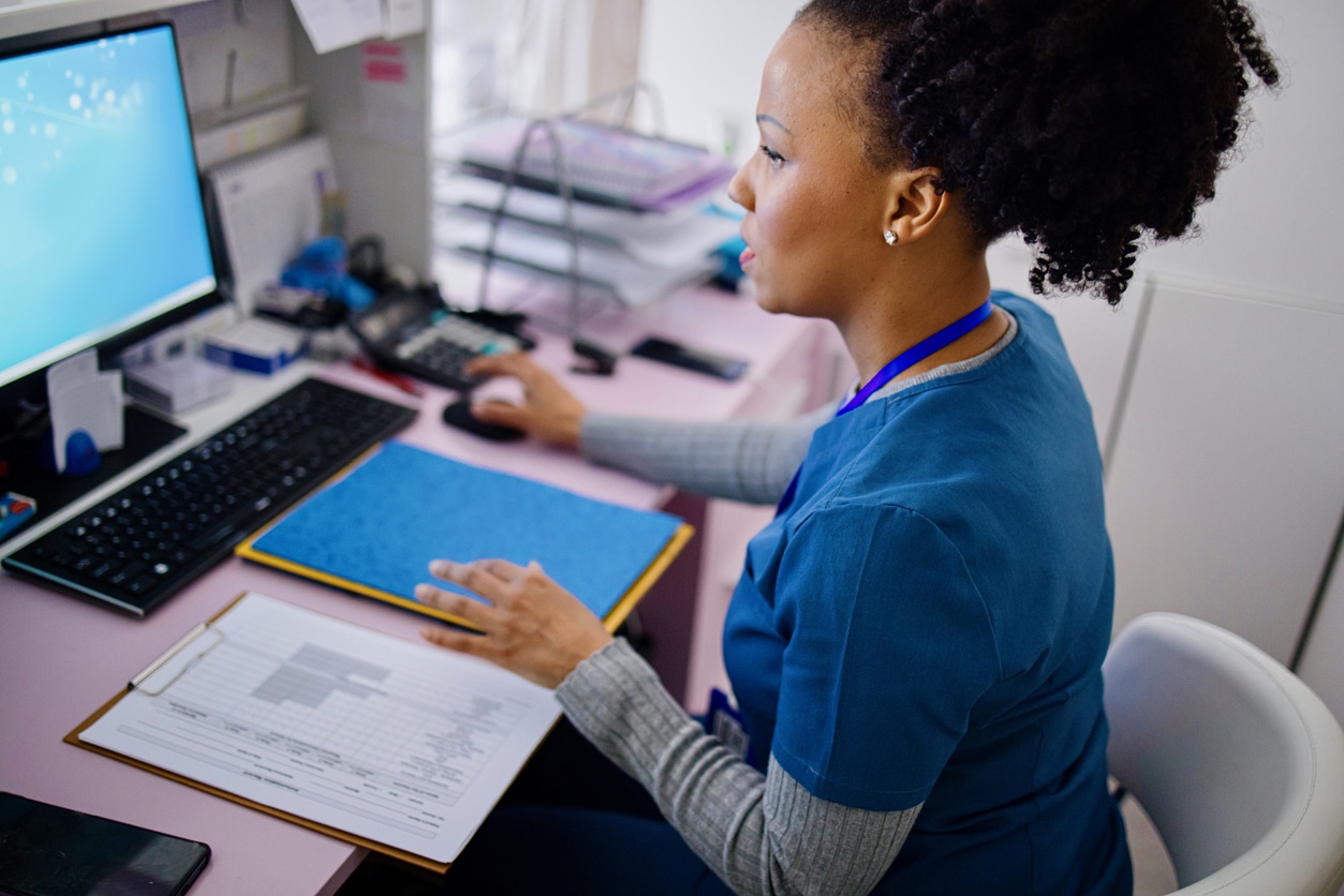 Black woman using computer to work as nurse in the private clinic understanding cybersecurity risks for healthcare offices
