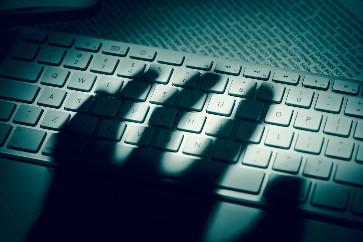 image of a shadow of a hand over a keyboard about to become a cyber threat