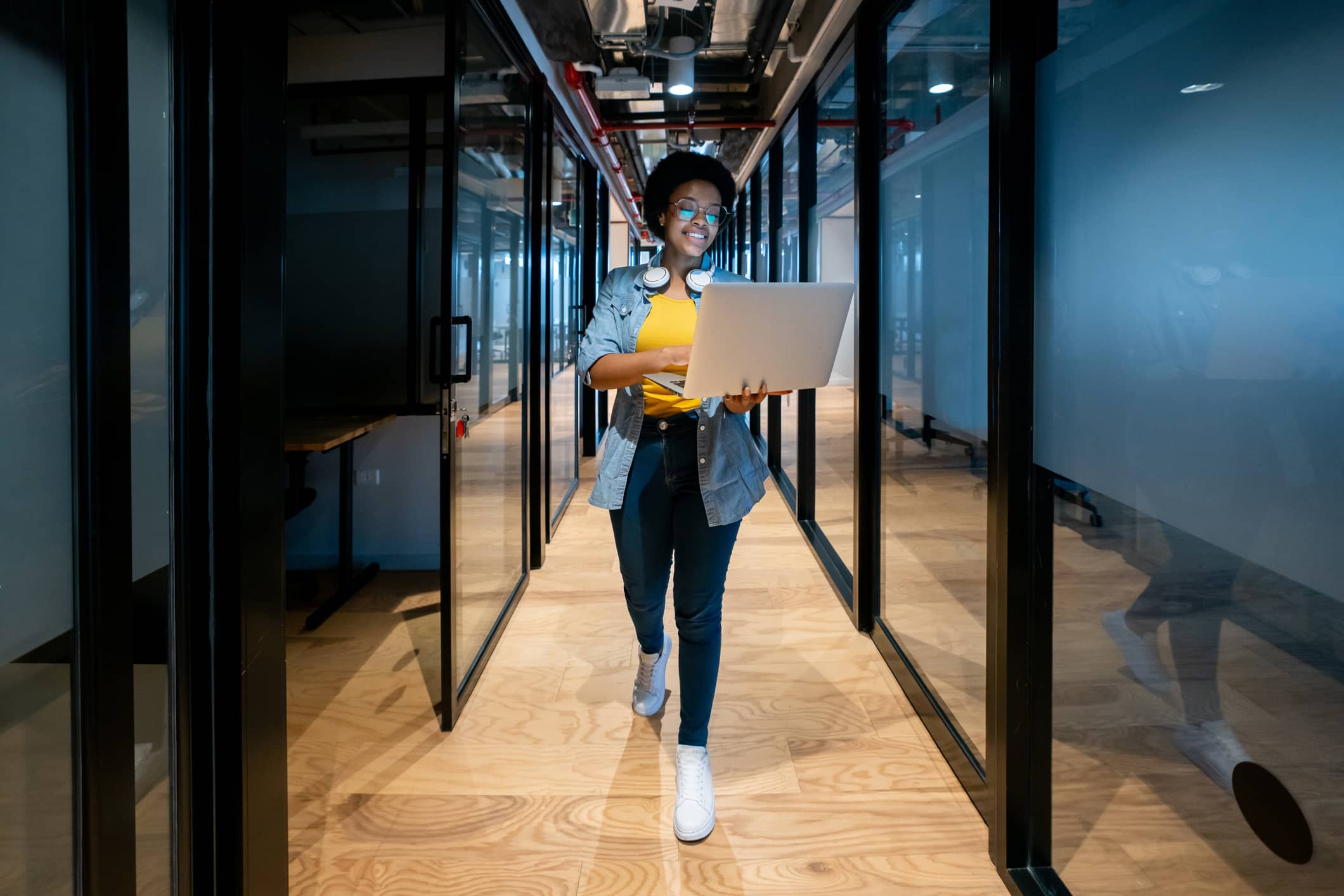 Attractive African American woman carrying a laptop through a business hallway