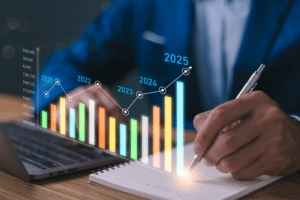 Business professional in a blue suit analyzing data charts and graphs representing yearly growth projections from 2021 to 2025. The digital overlay of a line graph and bar chart illustrates rising business trends, symbolizing the importance of building a Scalable IT Infrastructure for growing companies.