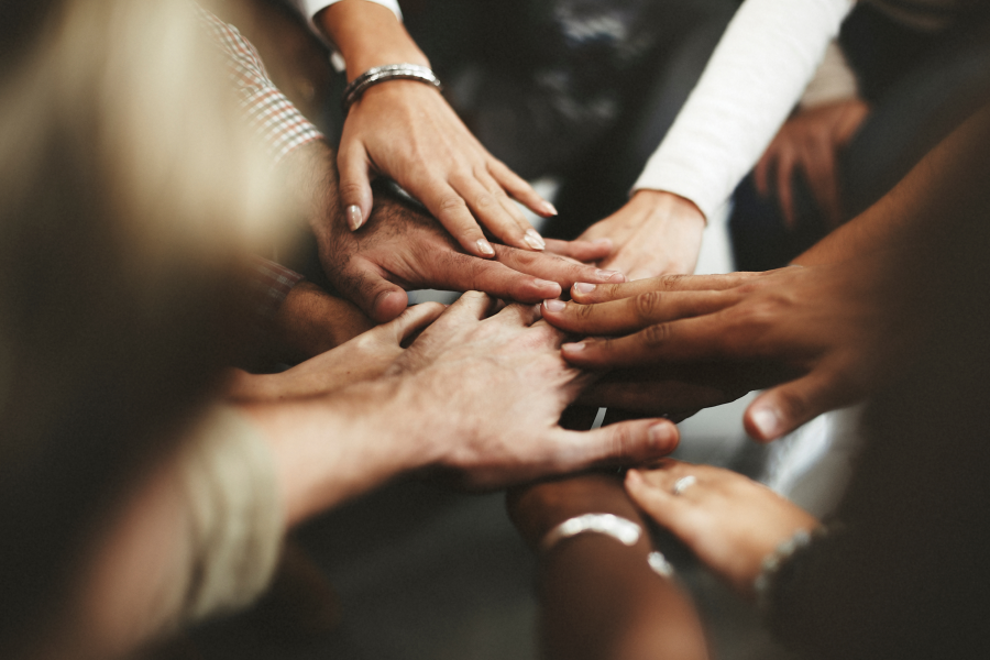 A diverse group of people joining hands in a circle, symbolizing unity and teamwork. IT Services Support Diversity, Equity, and Inclusion by fostering collaboration and connectivity among individuals from different backgrounds and experiences.